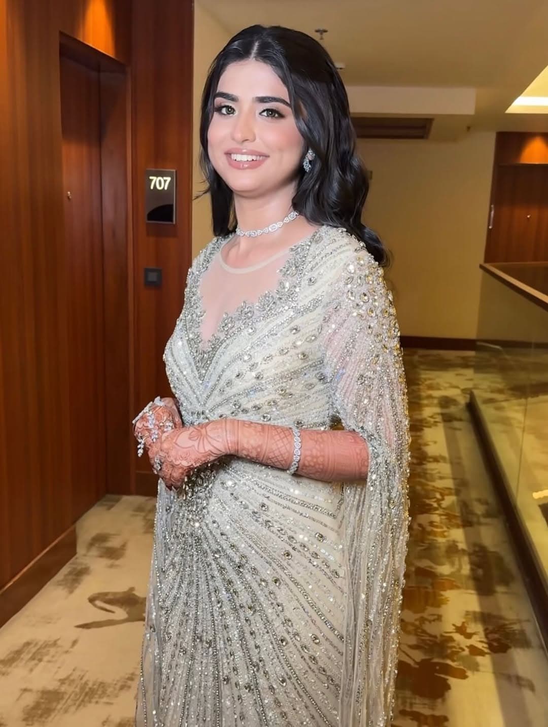 Sunlit bridal portrait with ornate gold jewelry, a sheer embroidered dupatta, and radiant red wedding styling